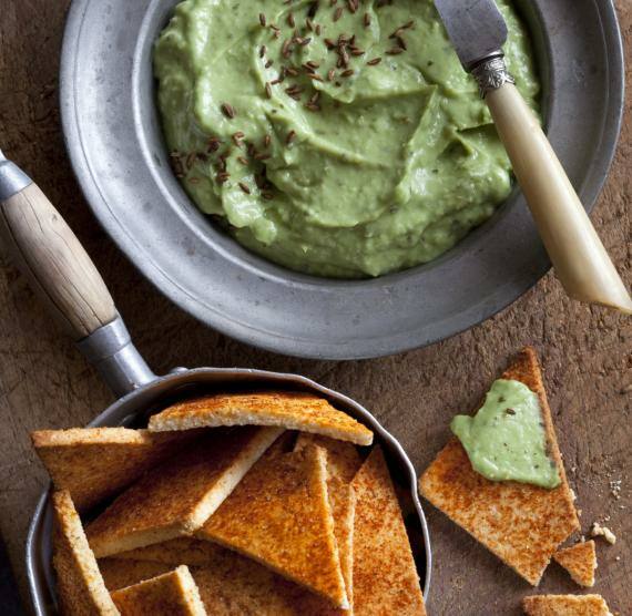 Pfännchen mit Crackern, daneben Avocadodip auf einem Teller