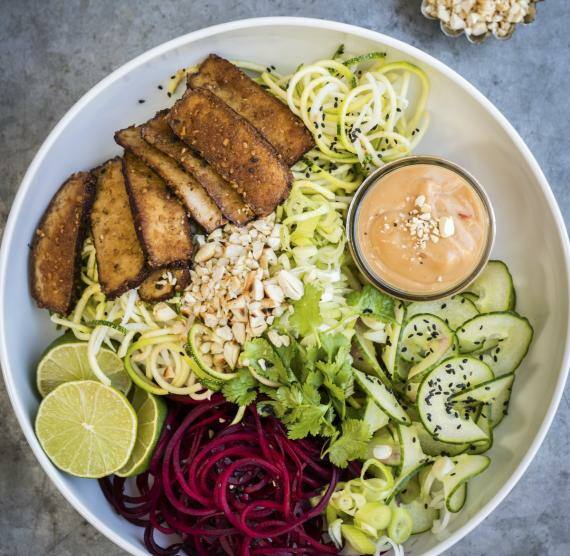 Gemüsespiralen mit Tofu und würziger Erdnusssauce in einer Schale