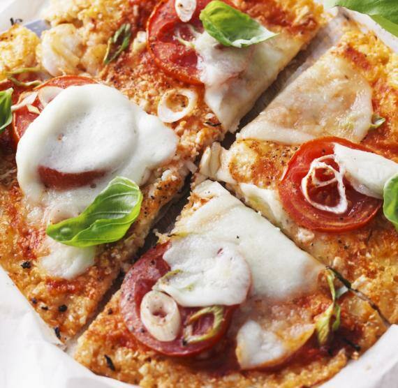 Geviertelte Pizza mit Tomaten, Mozzarella, Frühlingszwiebeln und Basilikum