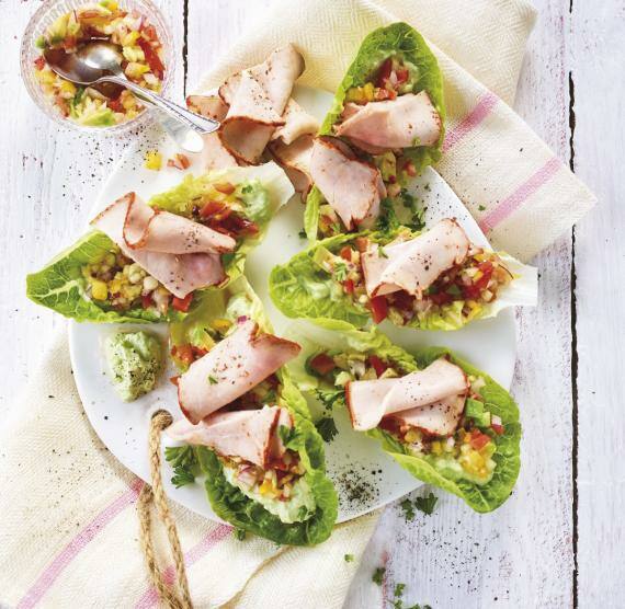 Salat-Tacos befüllt mit buntem Salat, Avocado und dünnen Scheiben Schweinebraten