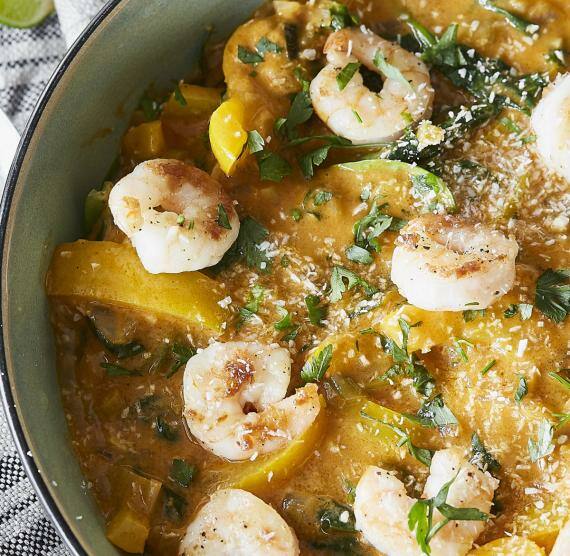 Schüssel mit gelbem Curry mit Shrimps, Paprika, Spinat und gehackter Petersilie