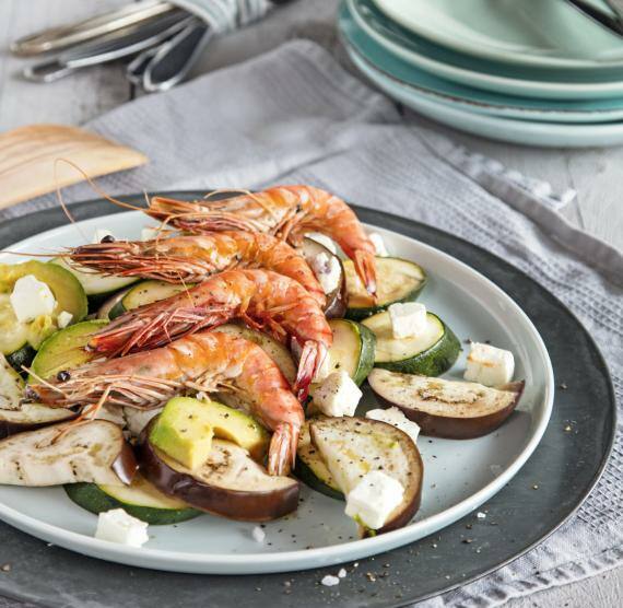 Teller mit Auberginen-, Zucchini- und Avocadoscheiben, darüber Riesengarnelen