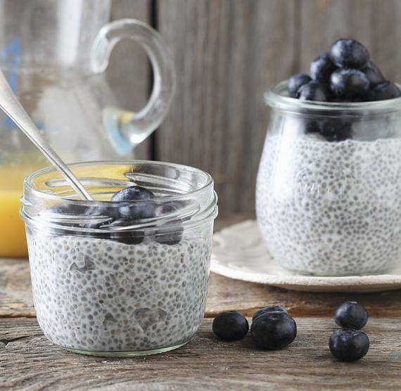 Chia-Pudding in Glas mit Beeren und Kanne mit O-Saft
