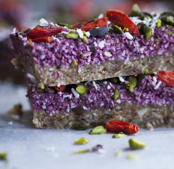 Zwei gestapelte Riegel mit Cashewboden und Rote Bete-Schicht, darüber Gojibeeren, Pistazien und Kokosflocken