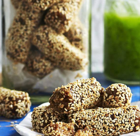 Nussriegel im Weckglas und auf Teller, daneben zwei grüne Smoothies mit Strohhalm