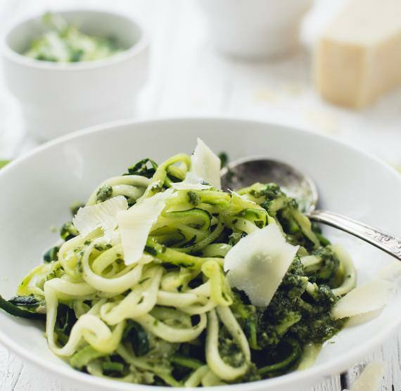 Weißer Teller mit Zucchininudeln, Basilikumpesto und Parmesanspänen
