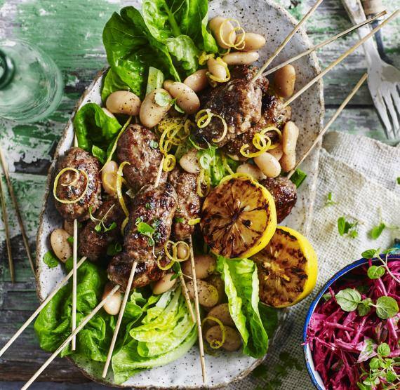 Lammspieße auf einem Teller mit Salat, weißen Bohnen und Rote-Bete-Tzatziki
