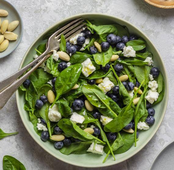 Teller mit Babyspinat, Blaubeeren, Mandeln, Feta und klarem Dressing