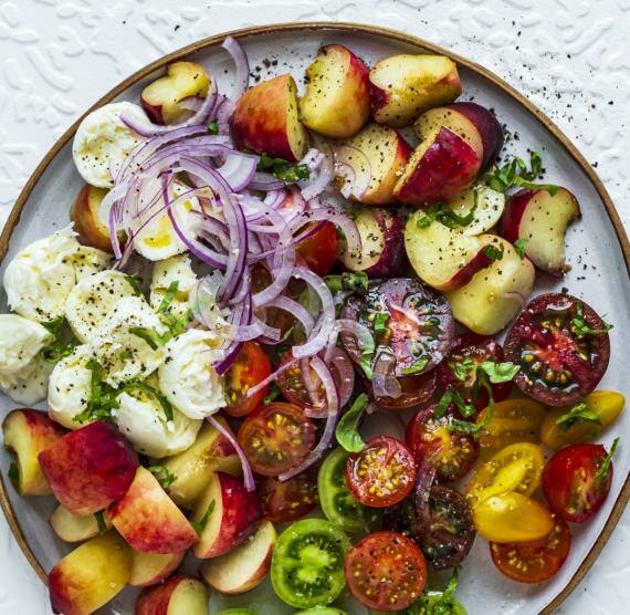 Salat auf Teller mit Tomaten, Plattpfirsich, Mozzarella und roten Zwiebeln