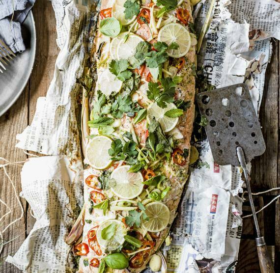 Fisch mit Zitronen auf Zeitungspapier,Teller mit Besteck und Pfannenwender