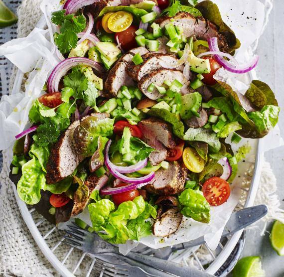 Avocado-Tomaten-Salat mit Schweinefilet auf hellem Papier in einem Korb