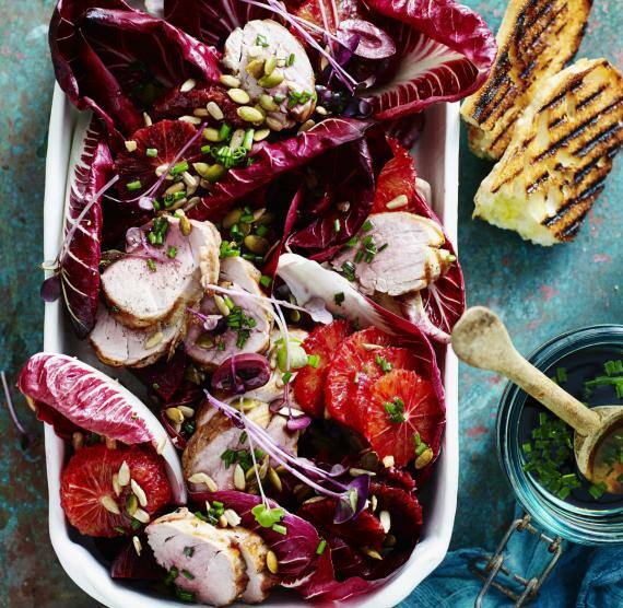 Rote-Bete-Salat mit Blutorangen und Schweinefleisch auf einem weißen Teller von oben