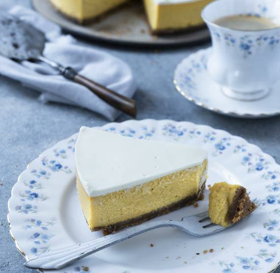 Stück Kürbis-Käsekuchen auf einem Teller mit einer Tasse Kaffee
