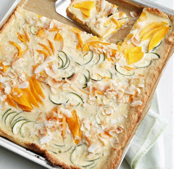 Mango-Kokos-Kuchen mit Zucchini auf einem Blech mit Backpapier