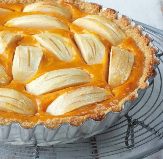 Möhrentarte mit Äpfeln auf einem Gitter, daneben Konfitüre in einem Glas