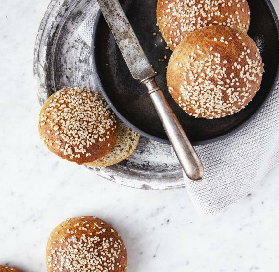 Sesam-Brötchen auf Teller und Tisch mit Messer
