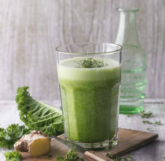 Grüner Smoothie in einem Glas auf einem Holzbrett