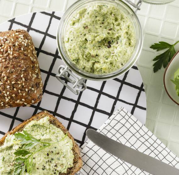 Schale mit Aufstrich und Brötchen auf einem Tisch