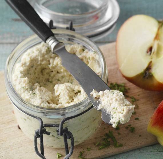 Glas mit Aufstrich, Messer und Apfel auf Brett