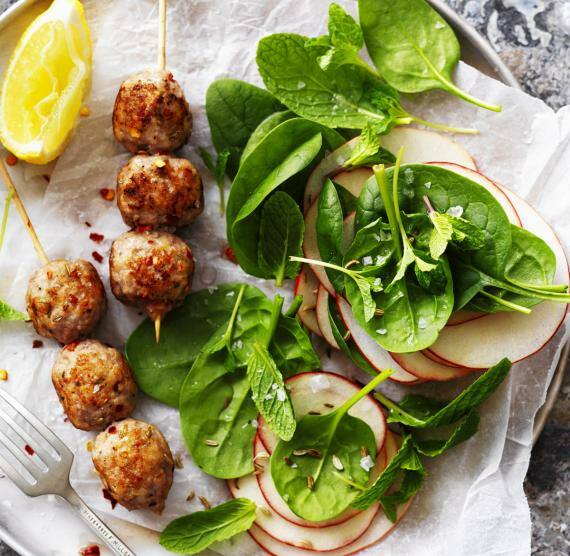 Spieße, Spinat und Äpfel auf einem Teller