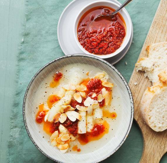Spargelcremesuppe in einem Teller, daneben Schale mit Tomatenöl