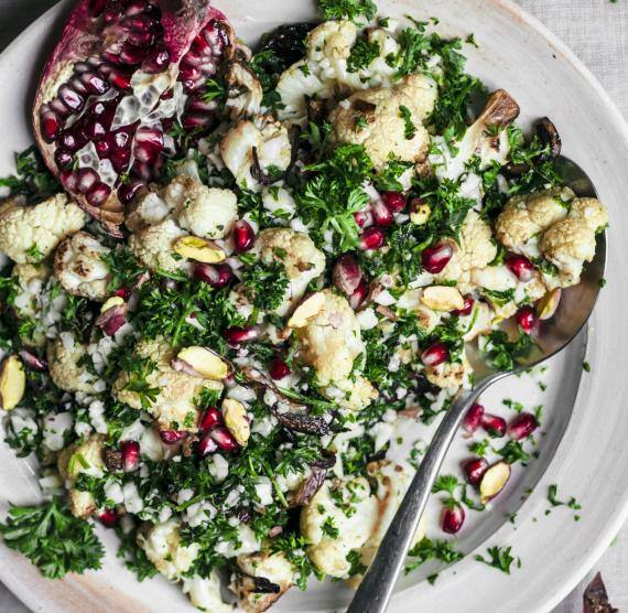 Salat mit Blumenkohl und Granatapfelkernen auf einem großen weißen Teller.