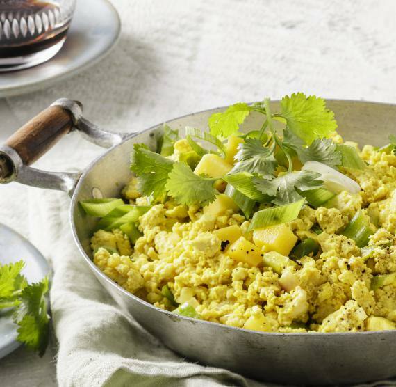 Veganes Tofu-'Rührei' mit Mango in einer schwarzen Pfanne.