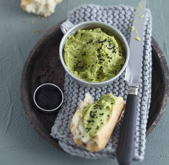 Hummis in einer Tasse und auf Brot mit Messer
