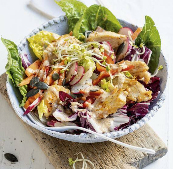 Hähnchensalat in einer Schüssel auf Holzbrett