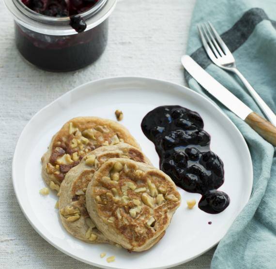 Bananen-Pancakes mit Walnüssen und Heidelbeersauce auf einem Teller