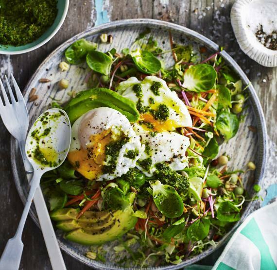 Salat mit pochiertem Ei auf einem Holzteller