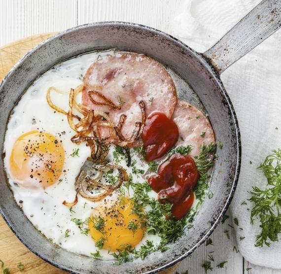 Spiegeleier und Würstchen in einer Pfanne