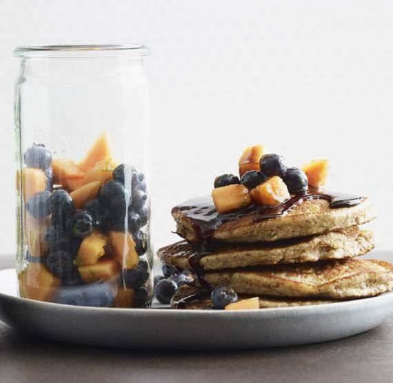 Pancakes auf Teller gestapelt mit Obstsalat im Glas