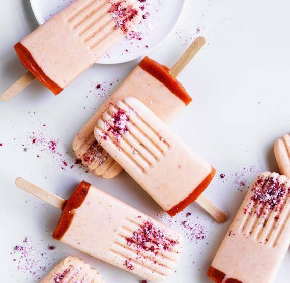 Rosanes Eis am Stiel auf Teller und weißem Hintergrund