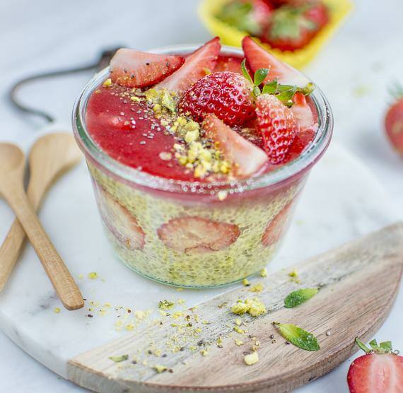 Weckglas mit Pudding und Erdbeeren auf Brett und Kochlöffel