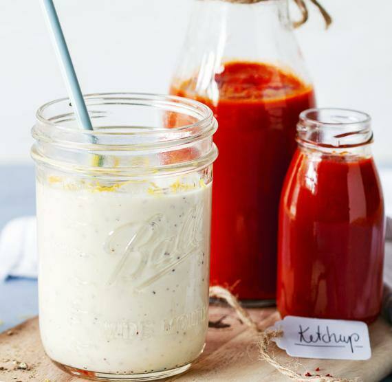 Glas mit Mayo und 2 Flaschen Ketchup auf Brett