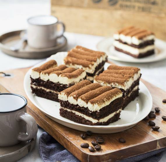 Tiramisu auf einem Teller und Brett mit Kaffeebohnen