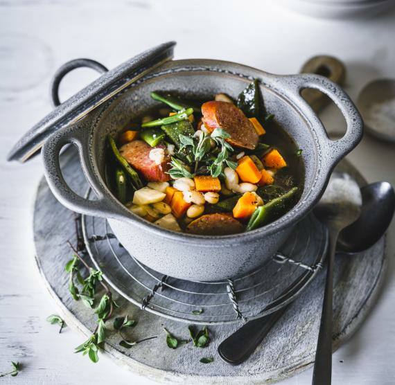 Grauer Topf auf Ablage mit Eintopf und Löffeln