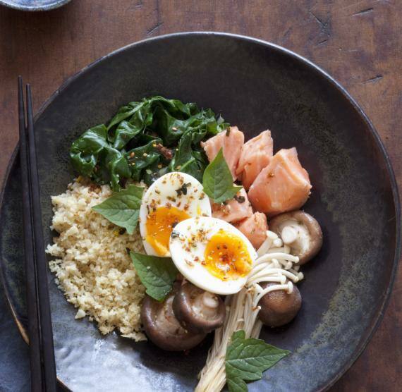 Blumenkohlreis, Pilze, Lachs und Ei in einer schwarzen Schüssel
