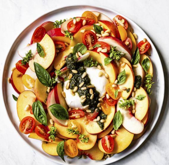 Mozzarellakugel umgeben von Obst und Gemüse auf einem Teller