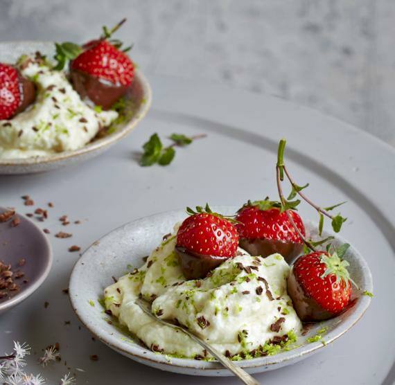 In Schokolade getunkte Erdbeeren auf einer weißen Creme in Schälchen