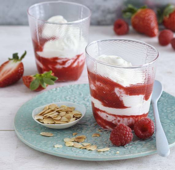 Gläser mit Cream und Beerenpüree auf Teller mit Mandelbättchen
