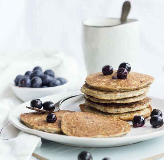Pancakes auf einem Teller gestapelt mit Blaubeeren und Tasse