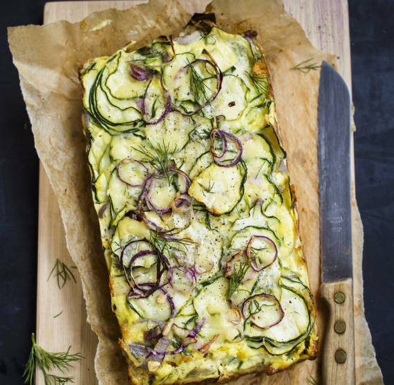 Zucchiniauflauf auf Backpapier und Brett mit Messer