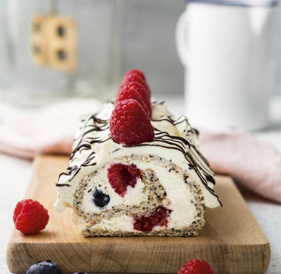 Biskuitrolle auf einem Brett mit Himbeeren verziert