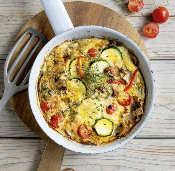 Helle Pfanne mit Gemüse-Frittata auf Brett, daneben Pfannenwender