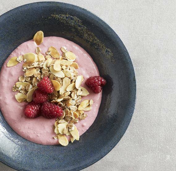 Quark in einer blauen Schale dekoriert mit Mandeln und Himbeeren