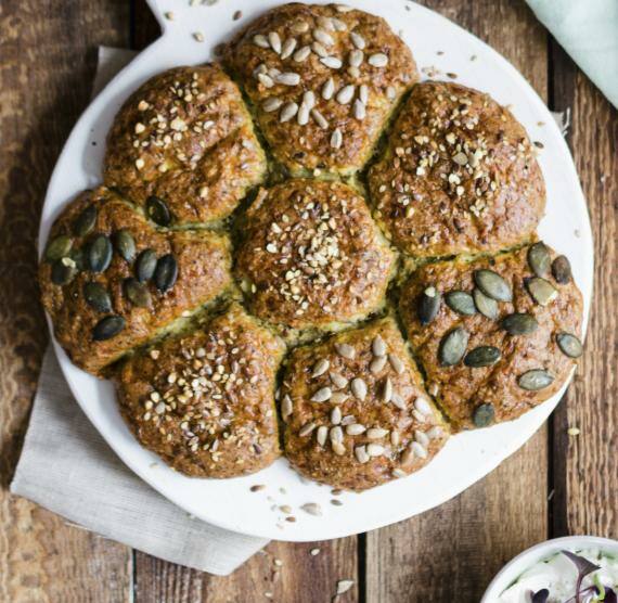 Brötchensonne mit Sonnenblumenkernen, Kürbiskernen und Leinsamen, daneben Kräuterquark und Messer auf Serviette