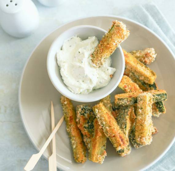 Weißer Teller mit panierten Zucchinisticks, dazu Mayonaise im Schälchen