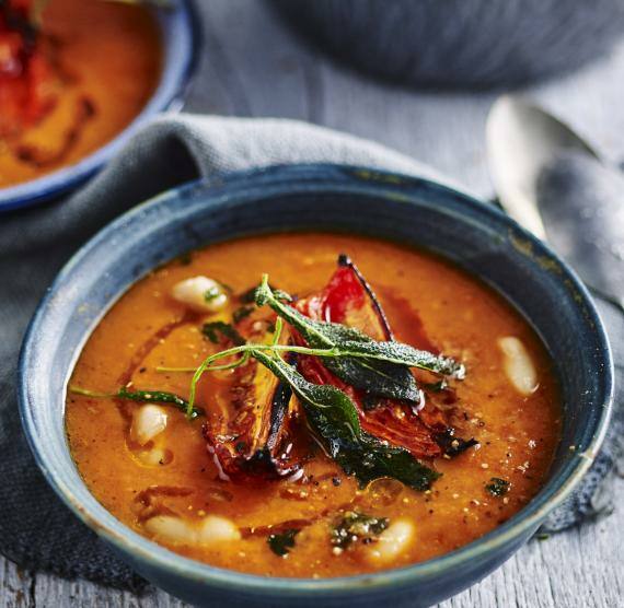 Topf und Schüsseln mit Tomatensuppe, darin Bohnen, Tomatenhälften und Salbei